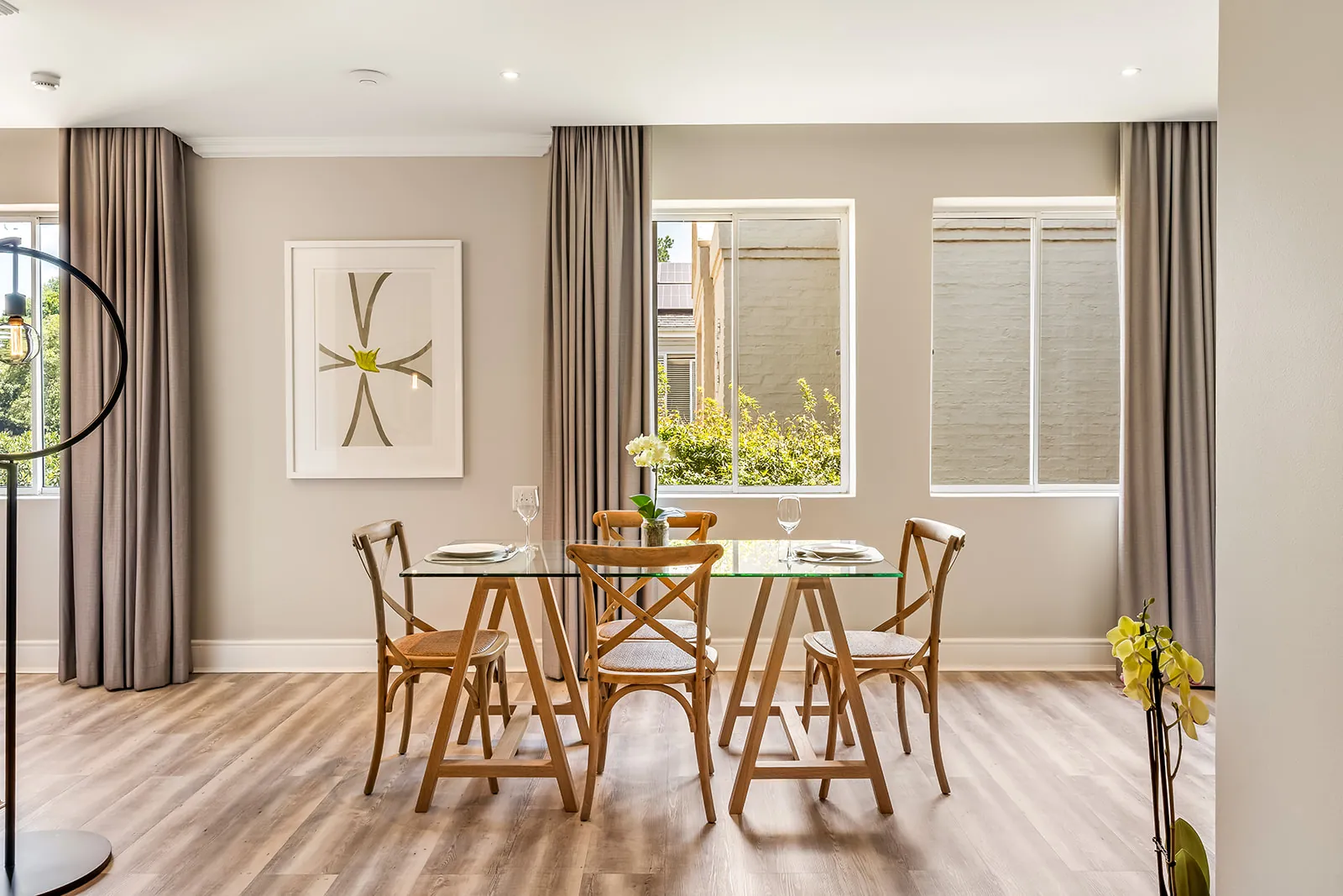 Elegant dining nook with framed art, glass table and floor-length curtains | Studio Stay on Sixty6 boutique hotel & accommodation in Sandton
